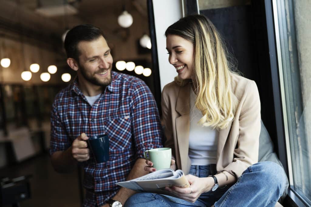 Zwei Kollegen unterhalten sich freundlich während der Pause mit einem Kaffee in der Hand